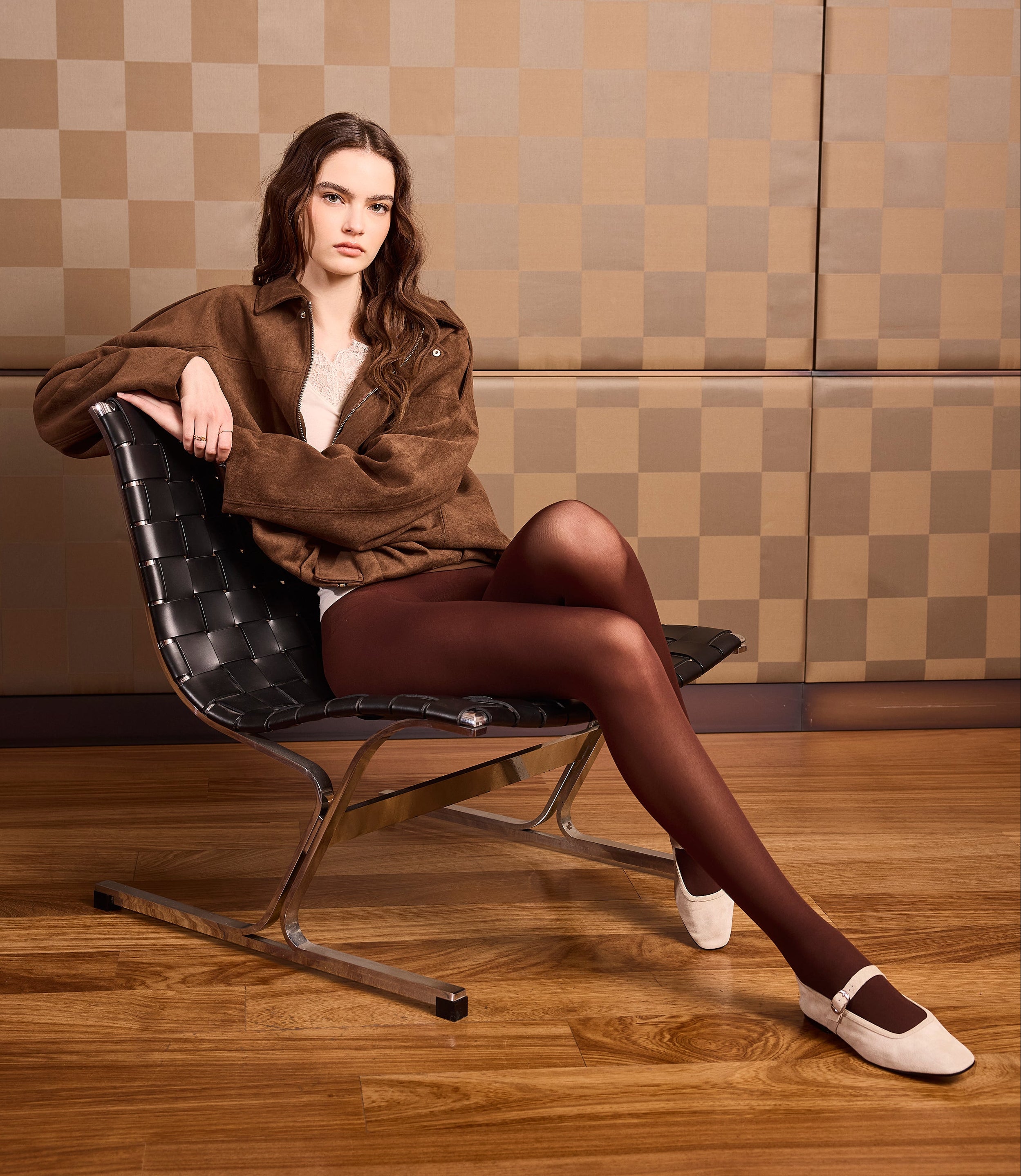 Ragazza che indossa una maglia color panna con cashmere a manica lunga. Scollo a V e polsini in pizzo. Collant coprente 50 denari con corpino senza cuciture color choccolate.