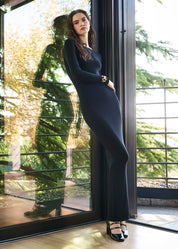 Ragazza che indossa un abito lungo nero con cashmere a manica lunga e scollo a barchetta. Collant velati 30 denari color playa nature.